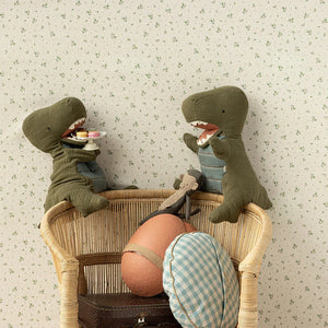Two toy dinosaurs in a wicker basket with a floral wallpaper background