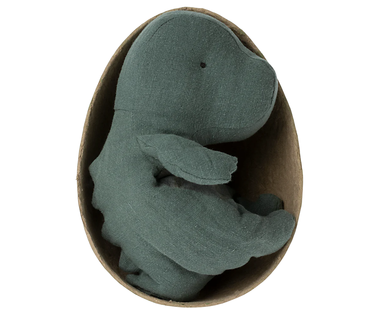 Green plush dino toy in a cardboard egg on a white background