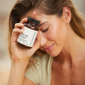 A woman holding a bottle f Glow with your Gut