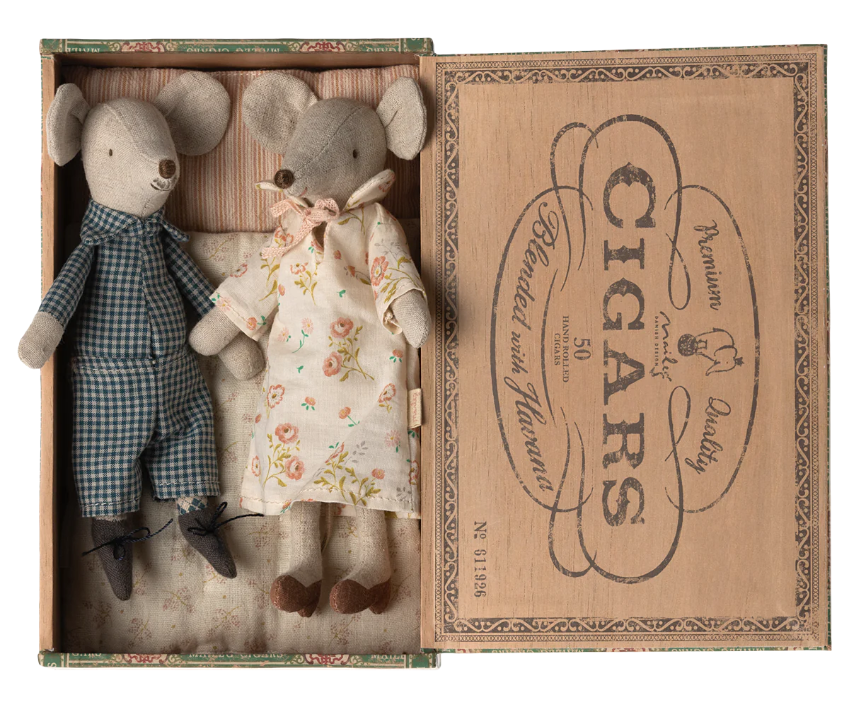 A set of two mouse figures, one in a blue checkered outfit and the other in a floral dress, placed inside an open cigar box with a brown interior.