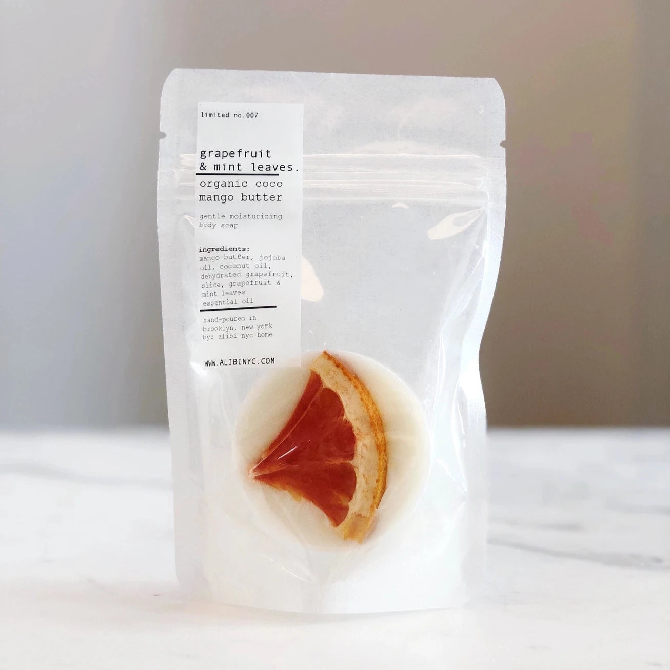White packaging of grapefruit and mint leaves soap on a white surface with a blurred background