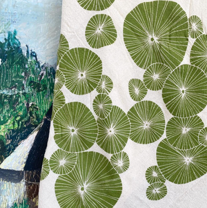 A green and white tea towel hanging in front of a piece of art. 