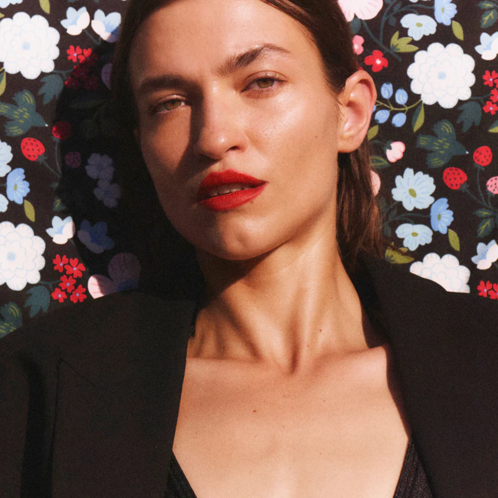 Woman with red lipstick against a floral patterned background