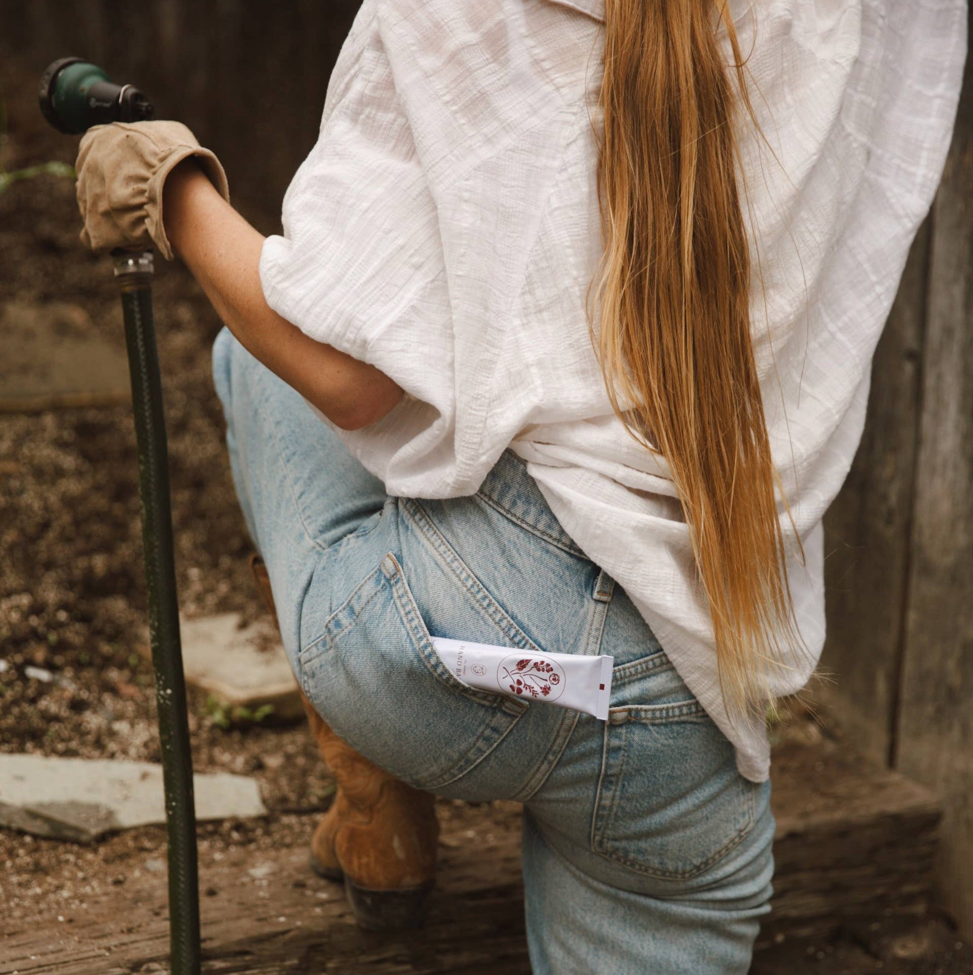 Person in light-colored shirt and jeans holding a walking stick on a wooden platform.