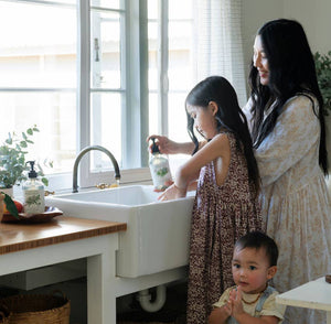 A happy family standing in front of the sink using koala eco hand soap. 