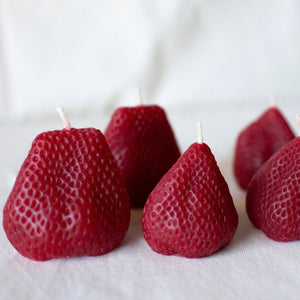 A group of Happy Organics Beeswax Strawberries on a cloth surface. 
