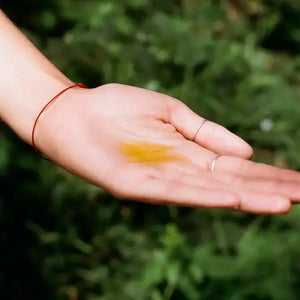 A person holding a sample of heat wave body oil in their hand. 