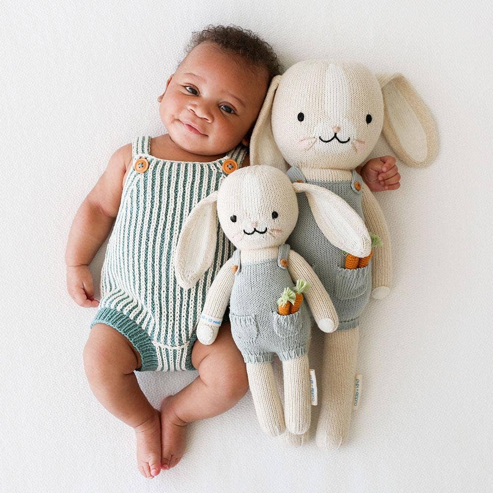 The cuddle and kind Henry the bunny stuffed animal in both sizes, with a baby wearing a striped onesie