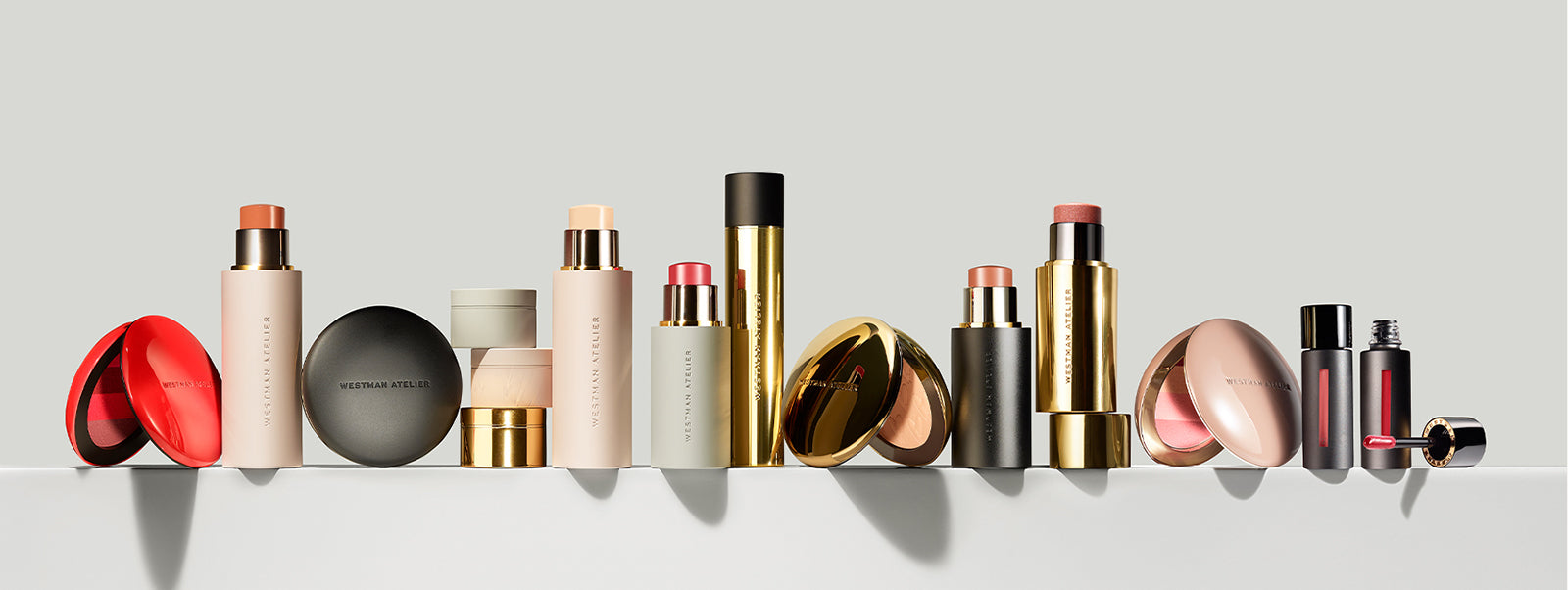 Row of various Westman Atelier cosmetic products on a light gray background