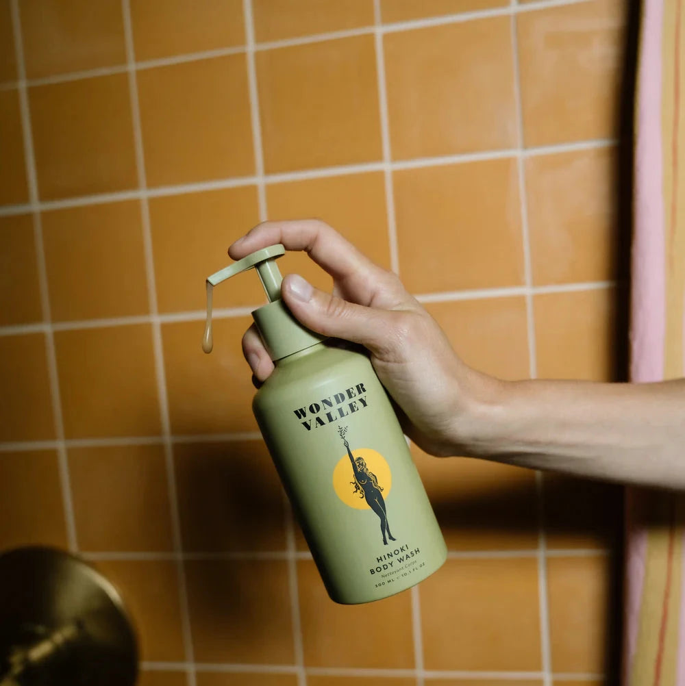 A person holding a bottle of the hinoki body wash, made by Wonder Valley in California