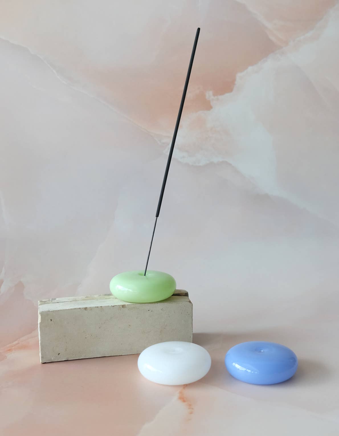 Incense stick on a white base with a white box against a plain background