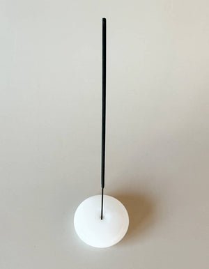 White spherical object with a black rod on a light gray background