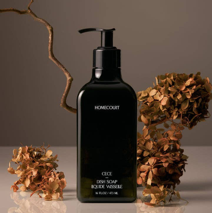 Black bottle of HOMECOURT dish soap with dried flowers on a neutral background