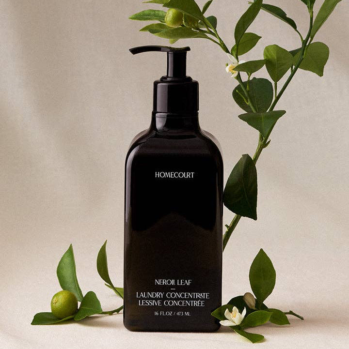 Black bottle of Homecourt laundry concentrate with dried flowers on a beige background