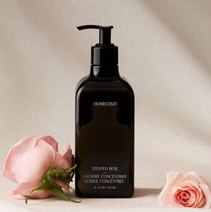Black bottle of Homecourt laundry concentrate with pink roses on a beige background