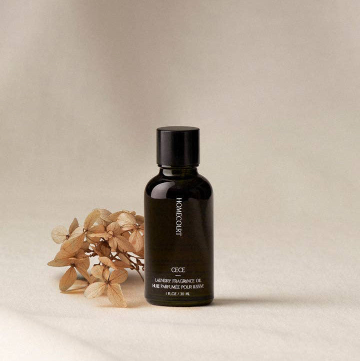 Black bottle of Homecure Art on a beige background with dried flowers.