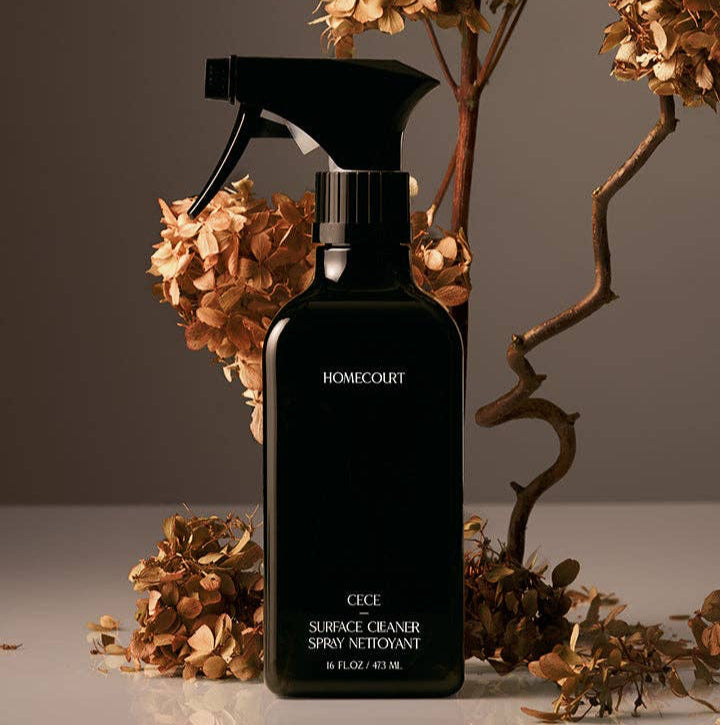Black spray bottle labeled 'Homecourt' with dried flowers on a neutral background