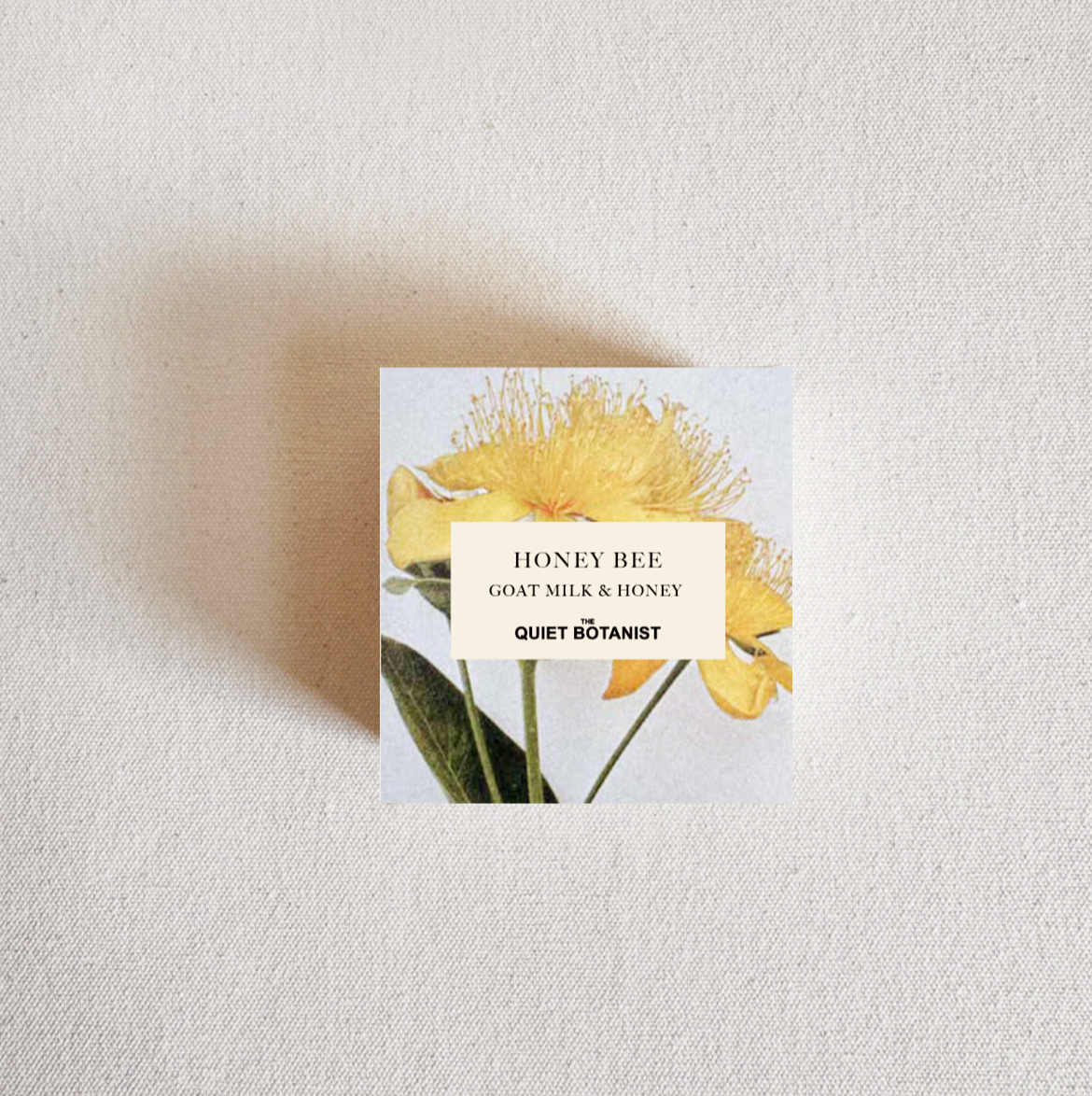 Small square product packaging with yellow floral design and text on a light gray background