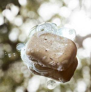 A bar of soap with bubbles on a blurred natural background