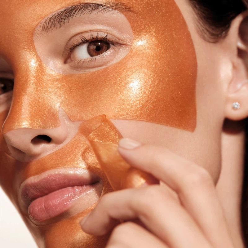 Close-up of a person applying an orange facial mask to their face.