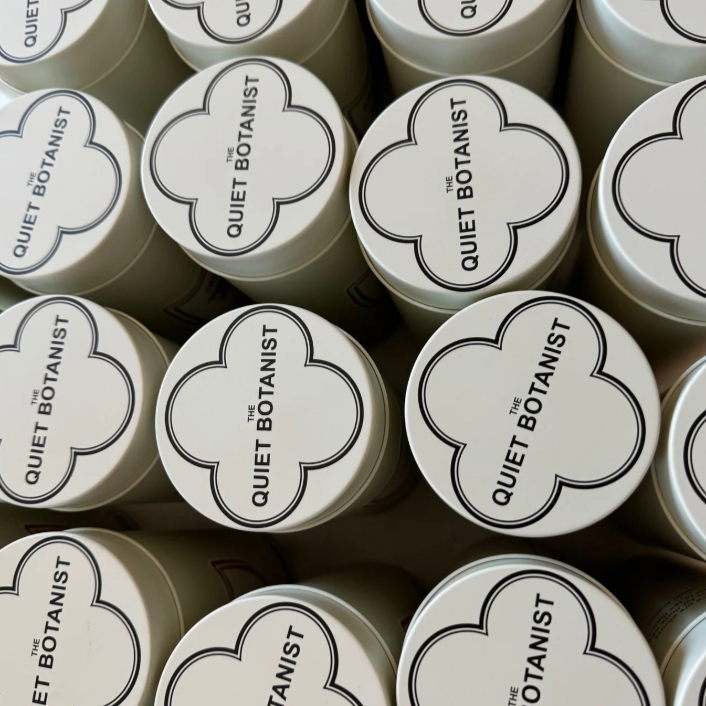 Multiple containers with 'Quiet Botanist' branding on a dark background