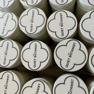 Multiple containers with 'Quiet Botanist' branding on a dark background