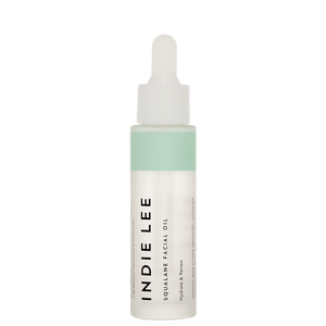 A bottle of Indie Lee Squalane Facial Oil with a white label and cap, contained in a clear glass bottle with a dropper.