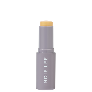 Cosmetic stick with beige cap and gray body on a white background, featuring 'Indie Lee' branding.