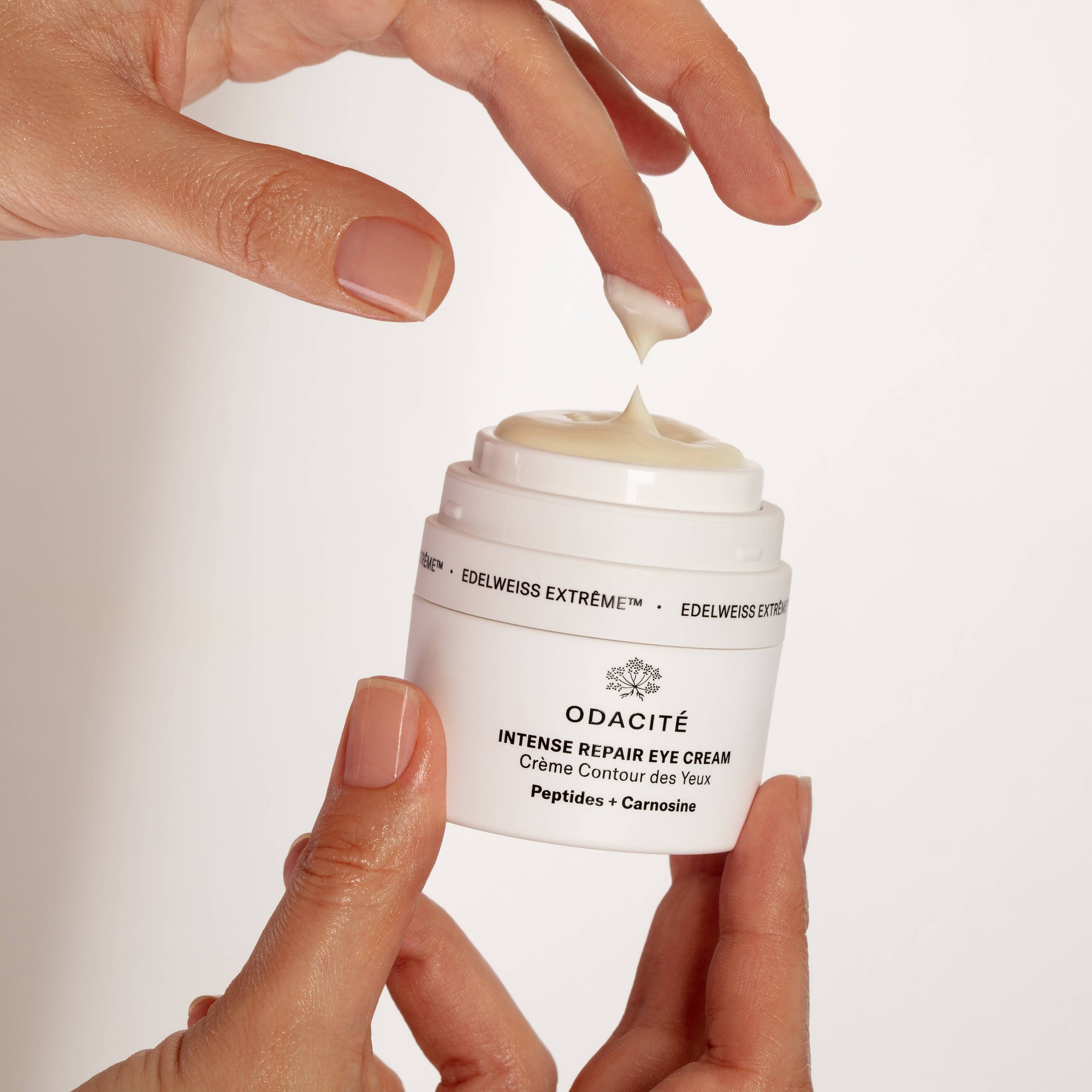 Person applying eye cream from a jar.