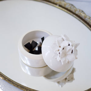 A white trinket jar on a mirror. 