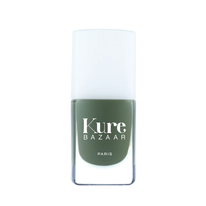 A bottle of Kure Bazaar nail polish in a khaki green shade with a white cap, labeled in Paris.