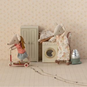 Two toy mice in a home setting with a scooter and laundry machine.