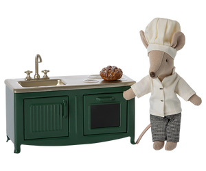 Toy mouse in chef outfit next to small kitchen set
