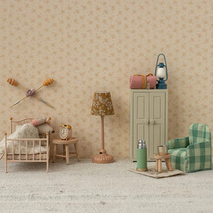 Miniature room setup with furniture and decor against a patterned wall.