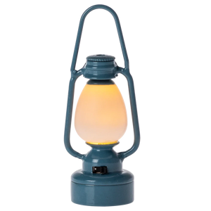 Blue lantern with a glowing yellow light on a white background