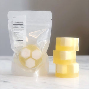 Packaged lavender product with a stack of yellow soaps on a marble surface.