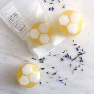 Yellow and white hexagonal soap bars on a marble surface with lavender flowers.