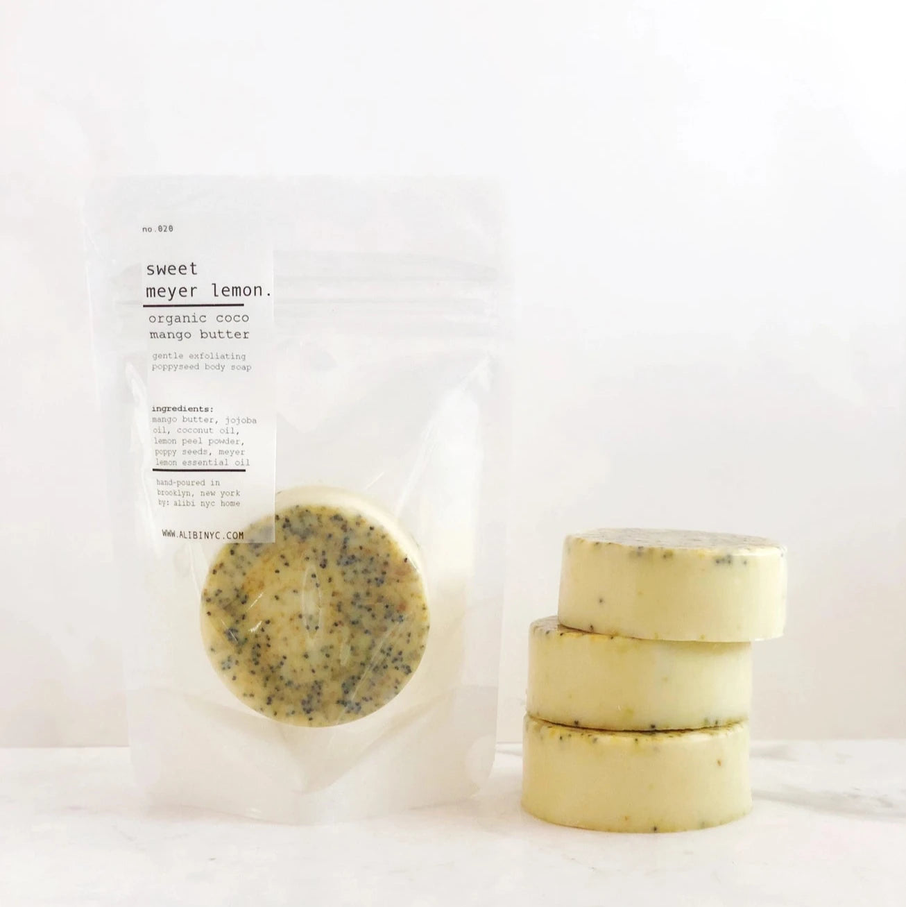 A stack of Meyer lemon soaps next to a rice paper bag with a lemon soap inside.