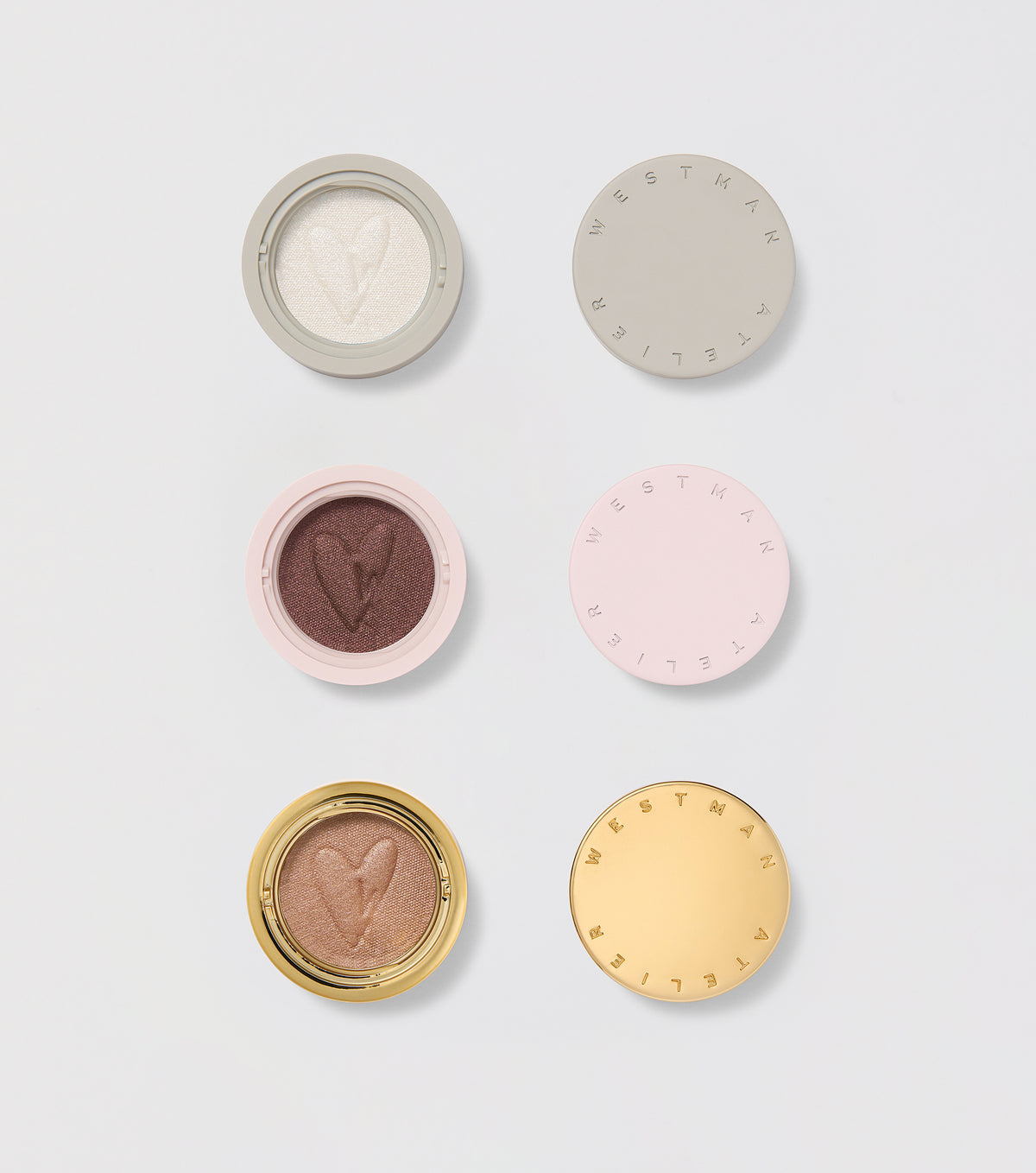 Three round eye shadow pods with a cream-to-powder consistency, displayed in natural shades with a golden, pink, and purple color scheme. Each pod has a unique texture with a logo at the center.