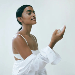 A person in a white shirt holding a bottle of Lesse regeneration mist