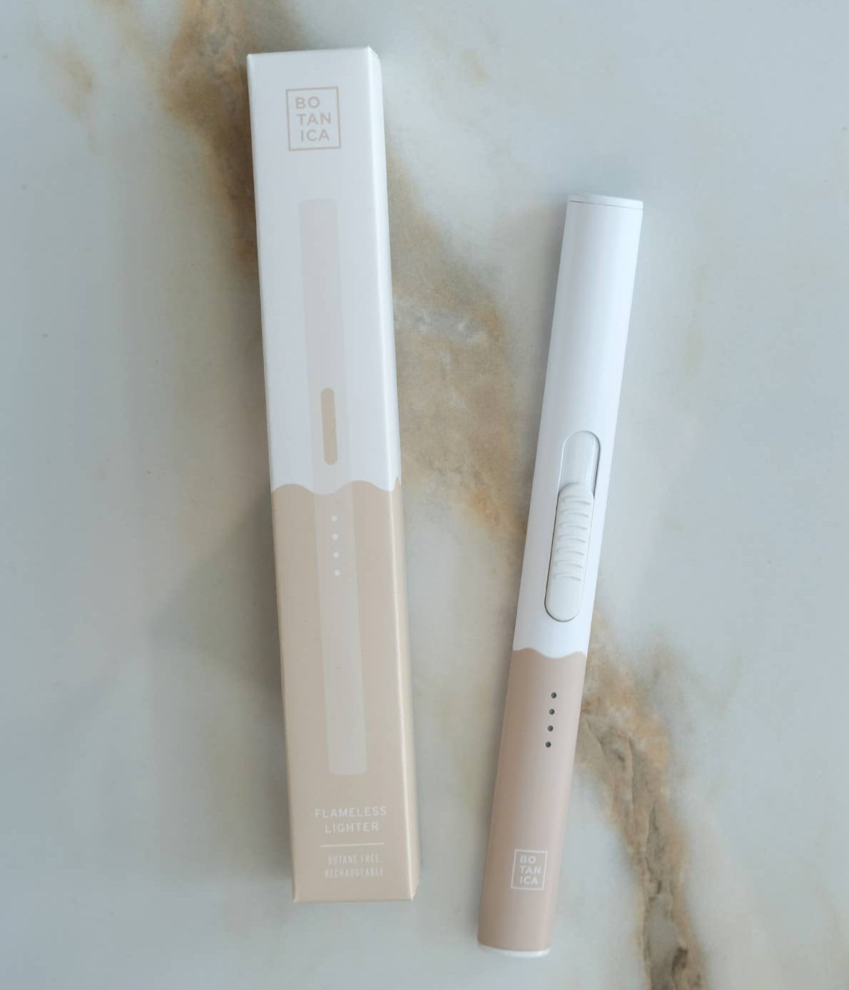 A brown and white box next to a Botanica flameless lighter, on a marble surface.