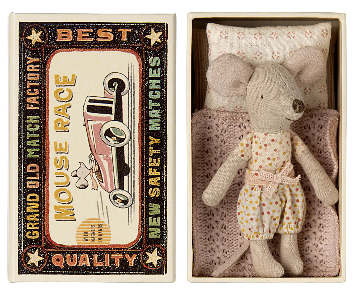 A toy mouse in a matchbox with the text 'Best Quality' on the cover, dressed in a polka dot outfit.