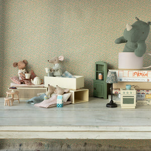 Miniature toys and furniture on a wooden surface with a patterned wall in the background