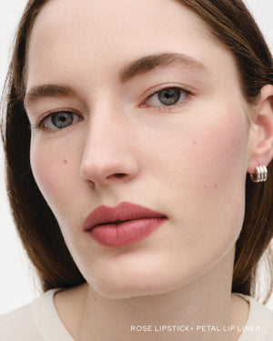 Close-up of a woman's face with rose lipstick and petal lip liner on a white background