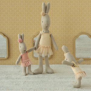 Three plush rabbit toys in a decorative setting with mirrors and patterned wallpaper.