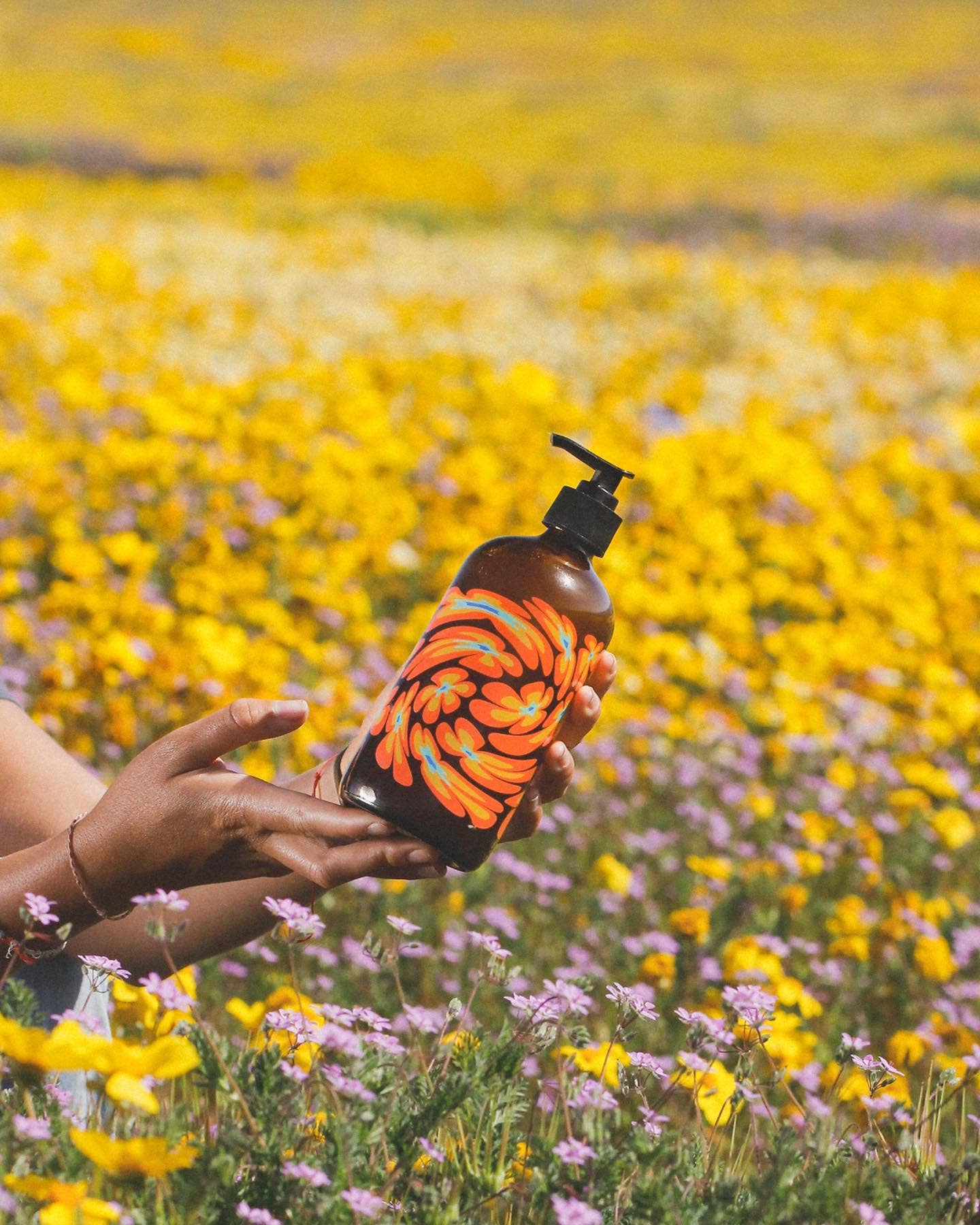 Brown bottle with colorful floral design and pump on a white background