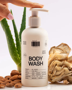 Body wash bottle with aloe vera, almonds, and mushrooms on a white background
