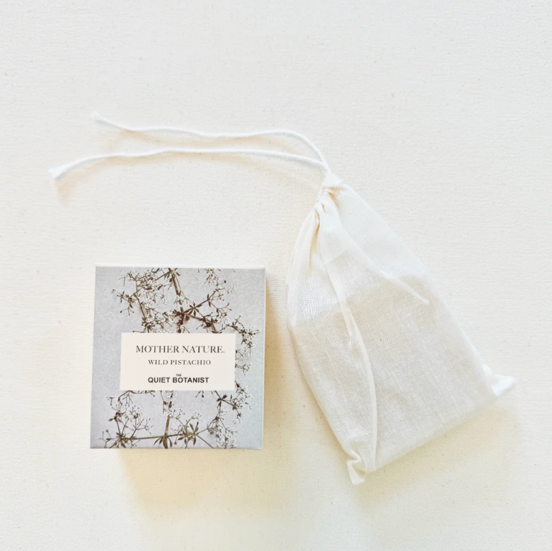A floral printed box with a label, next to a beige drawstring bag, on a white background