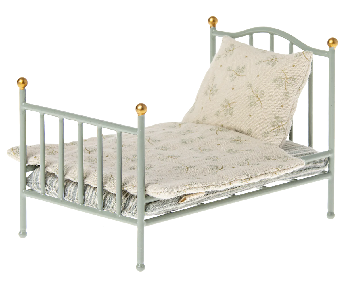A vintage style metal bed frame with a soft bedding set, designed for small toy mice.