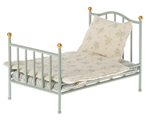 A vintage style metal bed frame with a soft bedding set, designed for small toy mice.